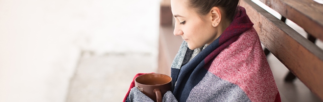 Girl in rug drinks hot tea in winter